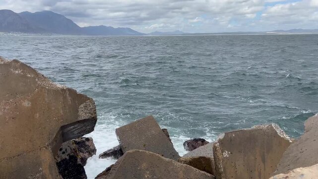 Waves crash agains the rocks and dolosse in a harbor