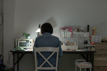 Asian woman working on handmade clay jewelry craft at home workspace