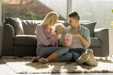 Couple playing with a dog and eating popcorn
