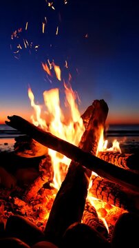夕暮れ時の岩の多いビーチで燃える焚き火と、それを背景にした海の波の美しい景色