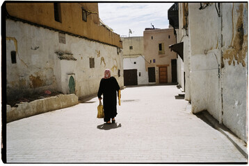 Film photo of a woman walking in a historic street in Morocco.