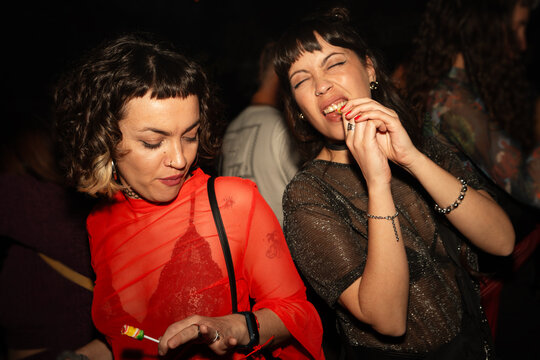 Friends dancing with drinks under flash light in a pub