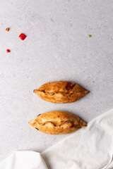 Overhead view of baked empanadas on a grey cement countertop, top view of empanadas or bolivian salte&ntilde;a