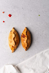 Overhead view of baked empanadas on a grey cement countertop, top view of empanadas or bolivian salte&ntilde;a