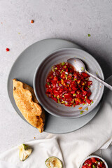 Overhead view of baked empanadas with pico de gallo on a grey plate, top view of empanadas and salsa, bolivian salte&ntilde;a with chopped tomato sauce
