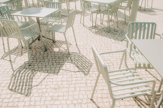 Outdoor metal chairs and tables casting dramatic shadows