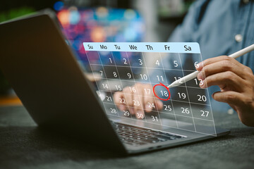 Person marking a date on a virtual calendar projected from laptop