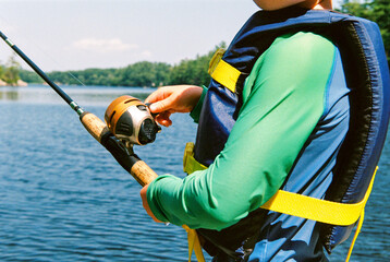 Child reeling in fishing line at the lake