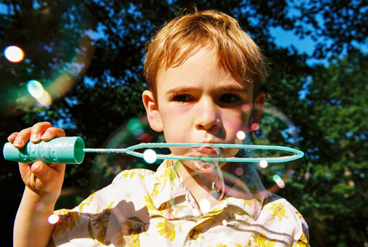 Portrait of Child Blowing Bubbles Outdoors 