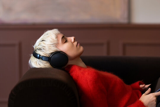 Blonde Woman Relaxing On Couch With Headphones Listening To Music