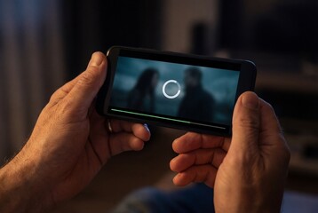 Man holding smartphone horizontally with buffering video screen showing loading icon and progress bar
