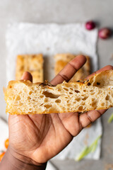 overhead view of sliced onion and scallion focaccia texture, top view of airy bubbly onion focaccia on a cement countertop, close up view on open crumb texture of bread