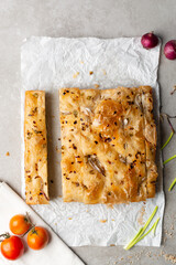 overhead view of slices of onion and scallion focaccia on parchment paper, top view of airy bubbly onion focaccia on a cement countertop