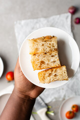 overhead view of sliced onion and scallion focaccia texture, top view of airy bubbly onion focaccia on a cement countertop, close up view on open crumb texture of bread