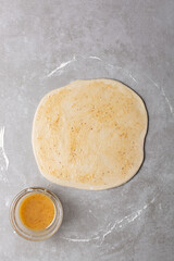 Overhead view of oil and flour mixture spread on raw chinese scallion pancakes dough, top view of homemade scallion pancakes, process of making cong you bing
