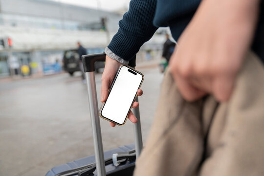 Man Checks Boarding Pass Outside Airport With Luggage in Hand