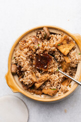 Overhead view vegan claypot rice with pan fried tofu, mushrooms and scallions, top view of crispy rice in a donabe on a marble countertop