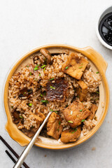 Overhead view of claypot rice with fried tofu and mushrooms in a spoon