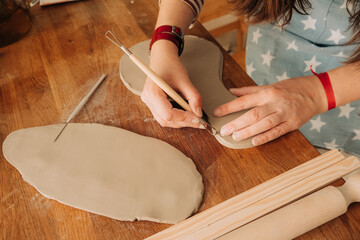 Detail carving work on clay piece using loop pottery tool