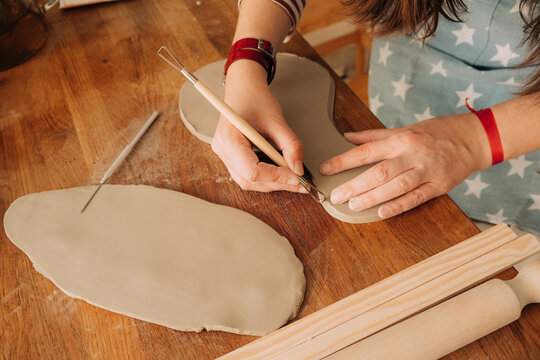 Detail carving work on clay piece using loop pottery tool