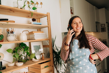 Smiling woman talking on phone at home in cozy kitchen setting