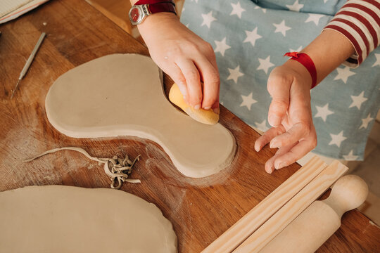 Smoothing clay edges with sponge during pottery handbuilding pro
