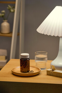 Pills and water on a nightstand with a lamp, promoting wellness