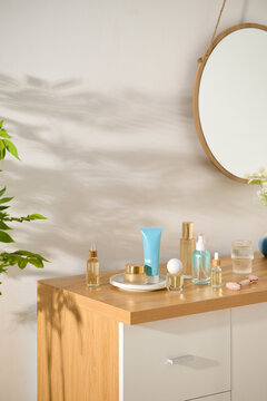 Skincare products arranged on a wooden vanity with a round mirror