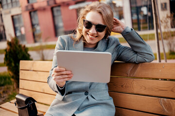 Business woman engineer on bench with tablet, spring break outdoors, corporate tech professional, remote work, smiling boss, city park.