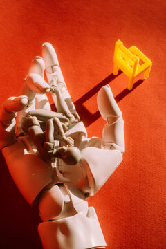 Robotic hand with tiny figures on orange