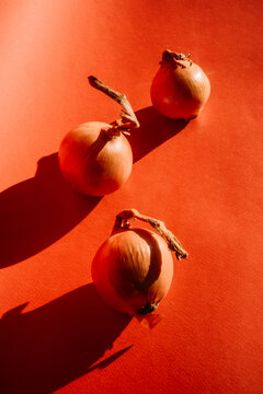 Onions on a red surface with distinct shadows