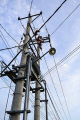 Concrete utility pole with complex wiring against a serene sky, casting shadows, suggesting dependable urban infrastructure