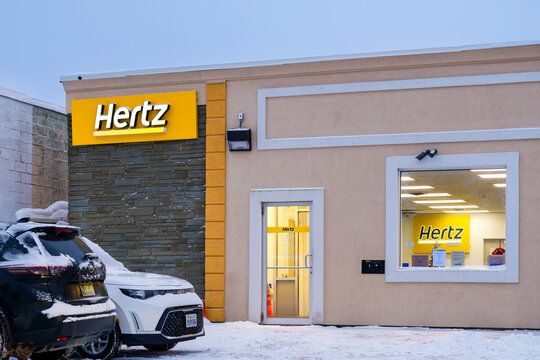 Yorkville, NY - Jan 5, 2026: Hertz, a U.S. car rental company founded in 1918, is shown with branded signage, snow-covered vehicles, and winter storefront visibility