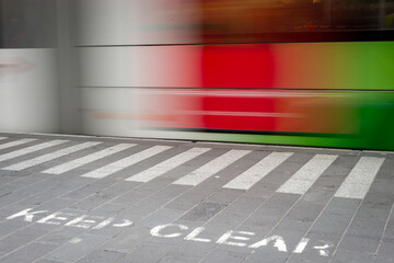 A Keep Clear notice in the forground with a train in motion in the background, train blurred and colorful