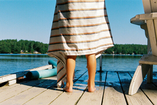 Child's feet on the dock by the lake with towel