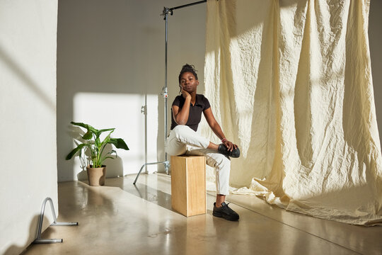 Model poses thoughtfully in studio setting with natural light