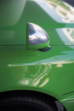 Close-up of green car fender with chrome mirror