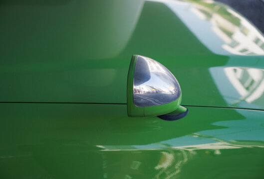 Close-up of green car fender with chrome mirror