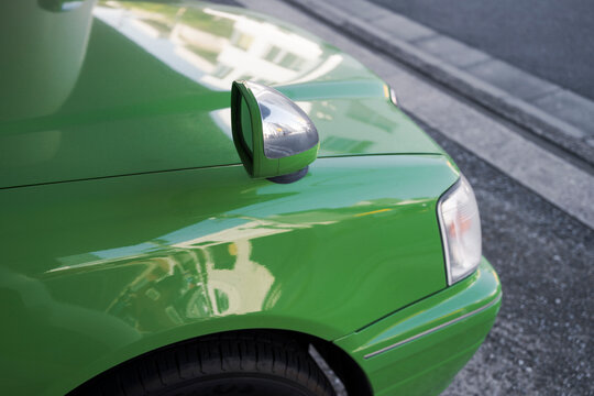 Close-up of green car fender with chrome mirror