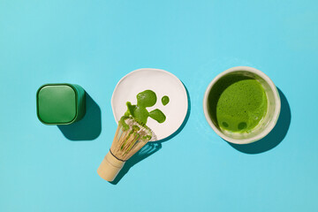 Top-down view of matcha tea preparation with a whisk and vibrant blue