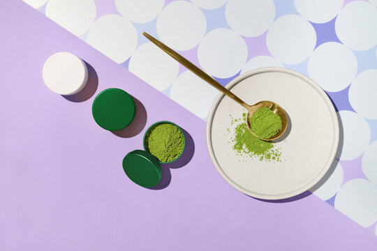 Overhead view of matcha powder with a golden spoon, lids