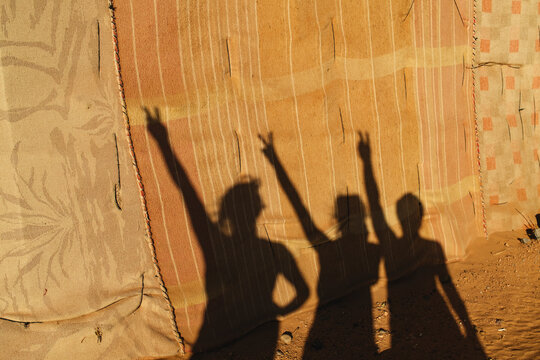 Three Human Shadows on Desert Fabric Wall
