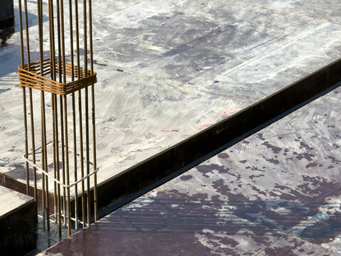 Column Rebar Rising from Glossy Formwork on Construction Floor