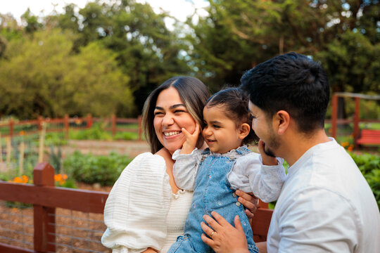 Little girl smiling with parents in garden setting