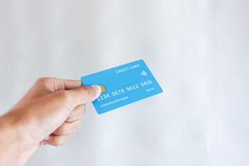 Hand holding a blue credit card against a light background. Financial transactions, contactless payments and modern banking concept. Secure online shopping and money management.