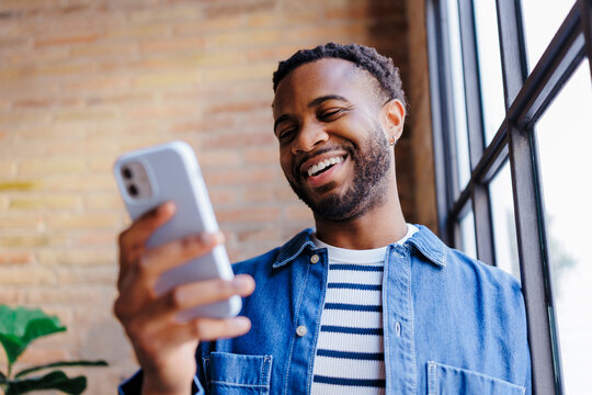 Man smiling, enjoying mobile phone content at office