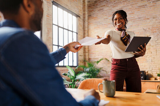 Woman colleague giving documents in office meeting