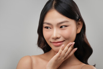 Beautiful Asian woman with flawless skin touching her face