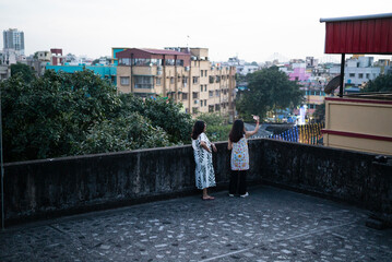 Two sisters taking selfie and making fun at rooftops of a high rise