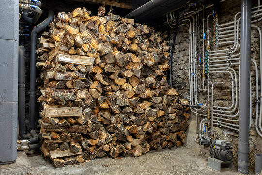 Stacked pine wood beside domestic firewood boiler installation
